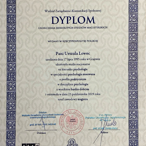 Dwóch uśmiechniętych pracowników w kaskach ochronnych i okularach (kobieta i mężczyzna) podczas pracy w hali produkcyjnej lub magazynie. Mężczyzna wskazuje na rząd metalowych paneli, a kobieta trzyma tablet, oboje ubrani w uniformy.