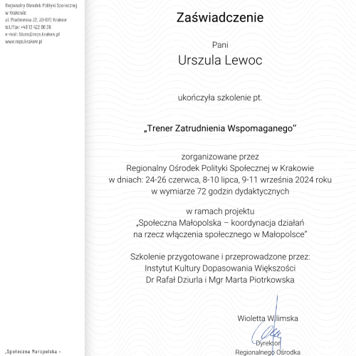 Widok na halę montażową fabryki samochodów, gdzie na taśmach produkcyjnych znajdują się nieukończone, srebrne karoserie samochodów bez kół i wnętrz. W tle widać jaskrawożółte elementy maszyn i linii produkcyjnej.